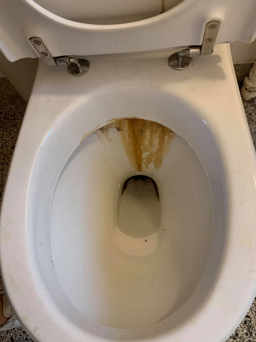 Toilet med tydelig orange-brun kalkstribe fra randen ned mod afløbet før afkalkning