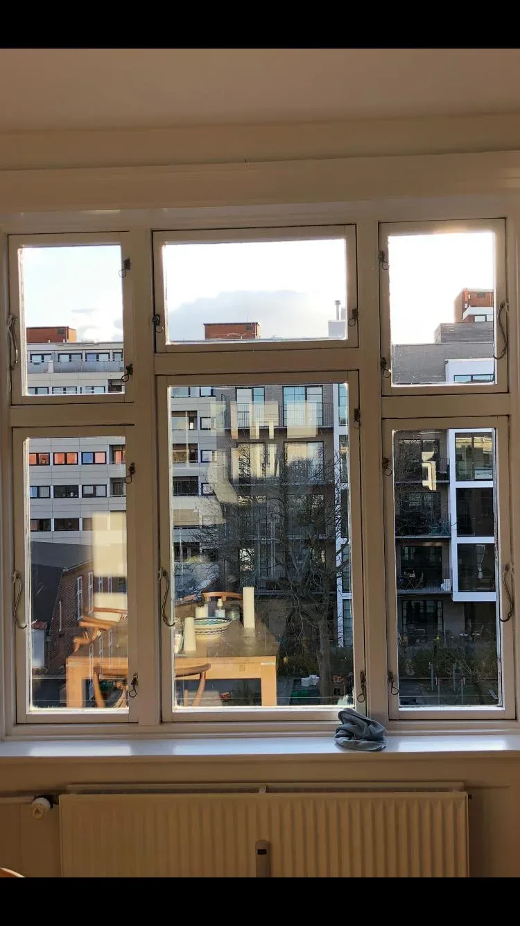Vindue efter pudsning — klart glas, skarp udsigt til naboejendom og balkoner